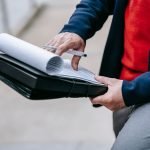 Close-up of a professional person reviewing documents outdoors. Engaged in work with focus on writing materials. — A Global S