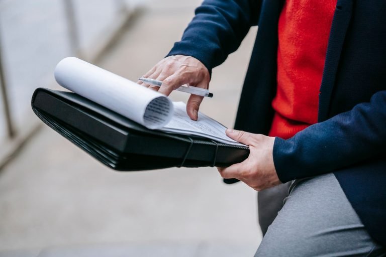 Close-up of a professional person reviewing documents outdoors. Engaged in work with focus on writing materials. — A Global S