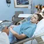 Caucasian woman in hospital bed receiving care from healthcare professional. — Cutting-Edge Treatments for Cardiovascular Con