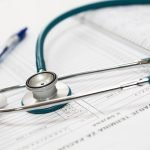 A stethoscope and pen resting on a medical report in a healthcare setting. — How to Buy Sustanon Safely and Legally