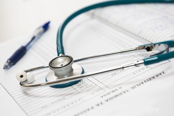 A stethoscope and pen resting on a medical report in a healthcare setting. — How to Buy Sustanon Safely and Legally