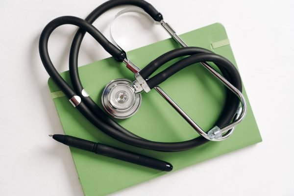 Top view of a stethoscope and pen on a green notepad, ideal for medical and educational themes. — Indulge in Blissful Relaxat