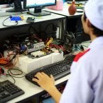 A technician in uniform working on a motherboard at a desk in a laboratory setting. — MetaTrader 4 WebTrader: Trade Directly