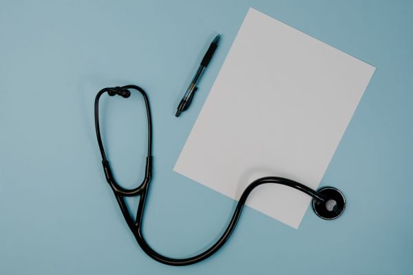 Flat lay of stethoscope, blank paper, and pen on blue surface — Understanding Testosterone Therapy: A Comprehensive Guide