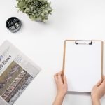 Flat lay of a home office desk with a clipboard, newspaper, and accessories. — Which Are the Best Medicare Advantage Plans in