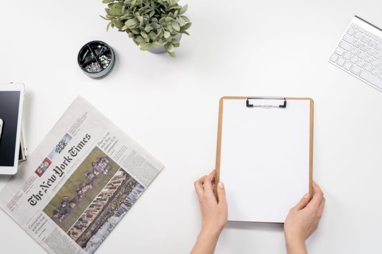 Flat lay of a home office desk with a clipboard, newspaper, and accessories. — Which Are the Best Medicare Advantage Plans in